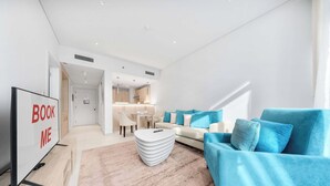 A modern living room with a sofa, a coffee table, and a TV stand. - StayShort - Prime 1 Bedroom Sleeps 2 in Palm Jumeirah (Dubai)