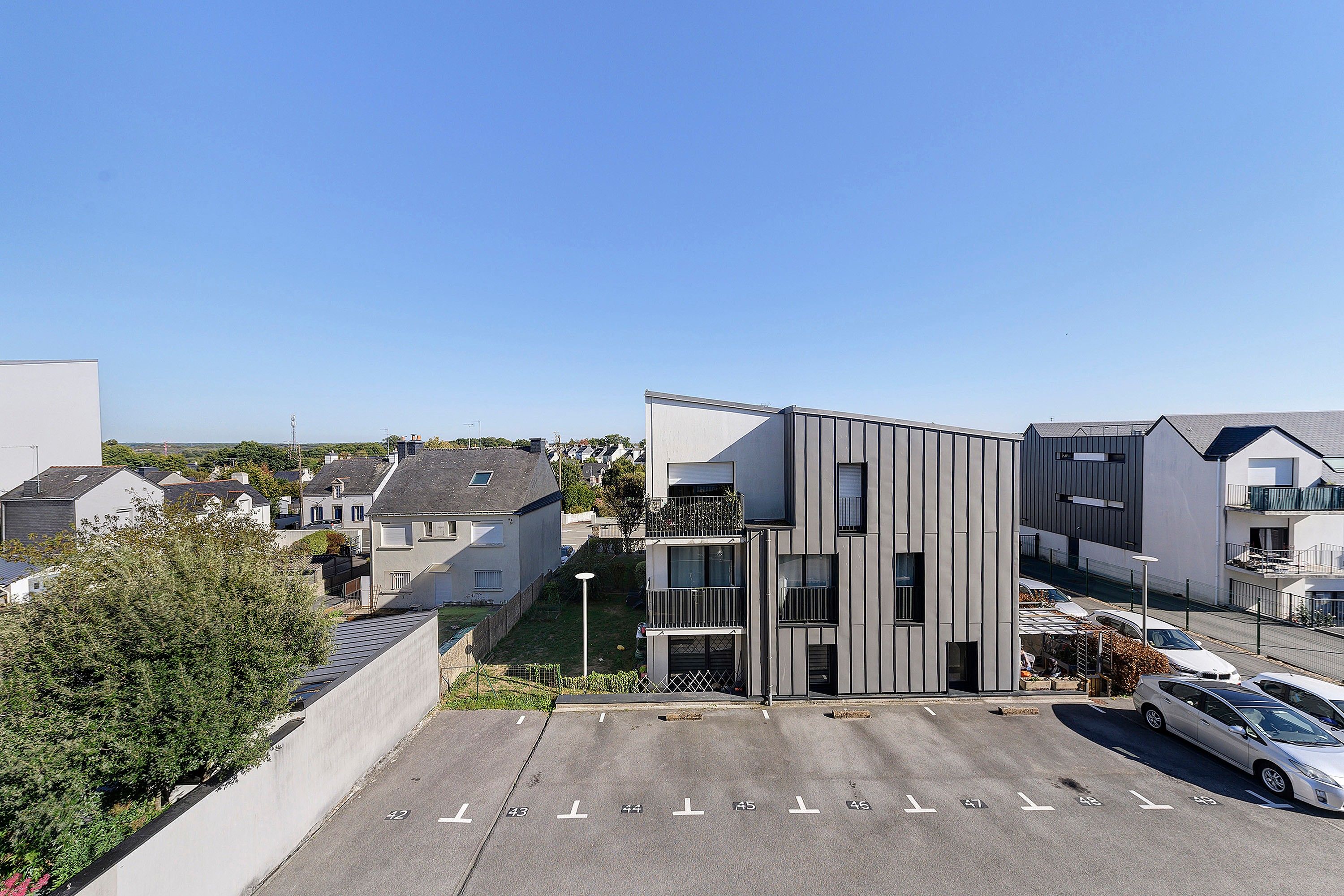 A modern building with a parking lot and a clear sky.