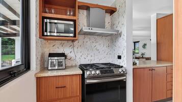 Eine moderne Küche mit Edelstahlherd, einer Mikrowelle und Holzschränken.