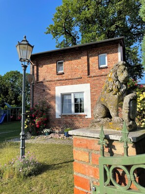 Une maison en briques avec une statue de lion, un lampadaire et une fenêtre.