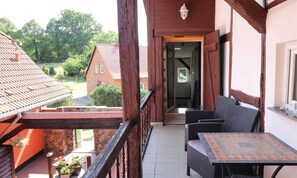 A balcony with wicker furniture and a tiled floor, overlooking a garden and neighboring buildings. - Gestrandet Vacation Home | Quiet Location | 20 Min. to the Baltic Sea | Sleeps up to 4 (Satow)