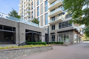 Een meerlaags gebouw met een bakstenen gevel, grote ramen en een voetpad.