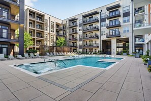 A modern apartment building with a rooftop pool, multiple balconies, and a landscaped garden area. - Stylish Stay Near Everything (Charlotte)