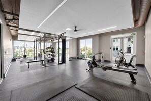 Een sportschool met trainingsapparatuur, een roeimachine en een bank.