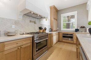 Una cocina moderna con estufa a gas, horno y armarios de madera.