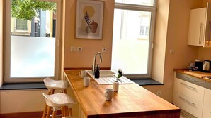 A modern kitchen with a central island, bar stools, a sink, and a window with a view.