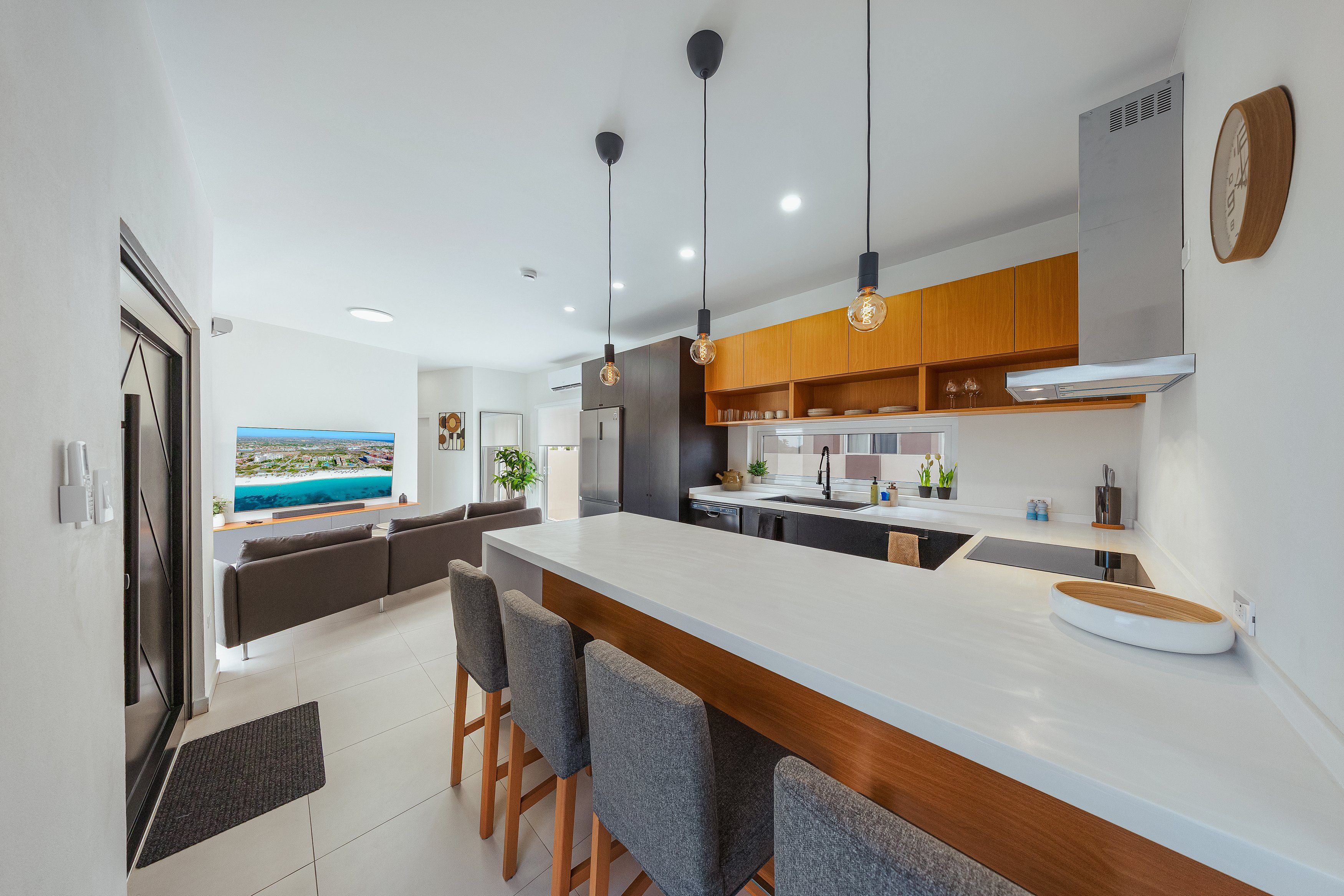 Cozinha moderna com ilha central, bancada para refeições e vista para a praia.
