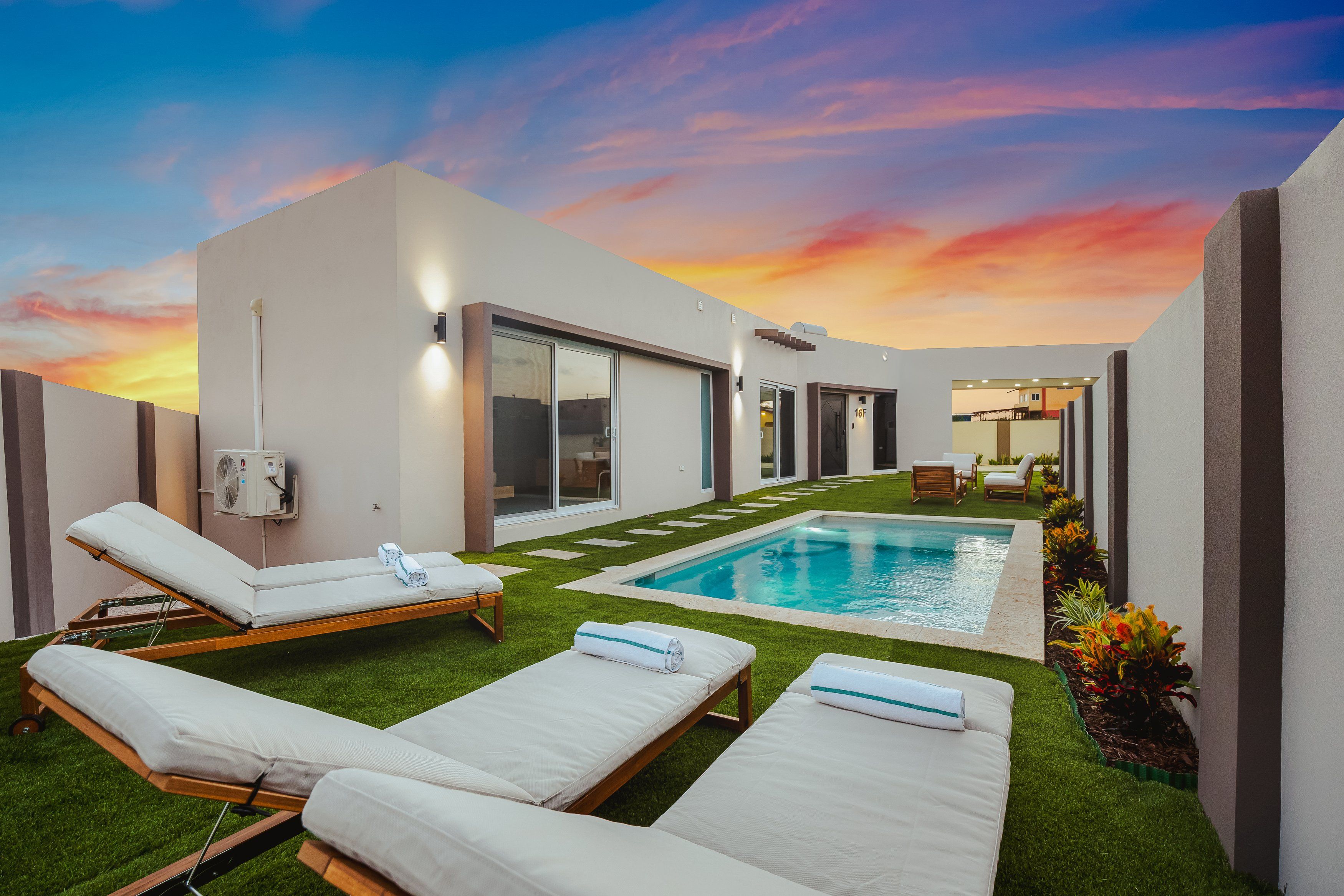 A modern outdoor pool area with lounge chairs and a clear sky.