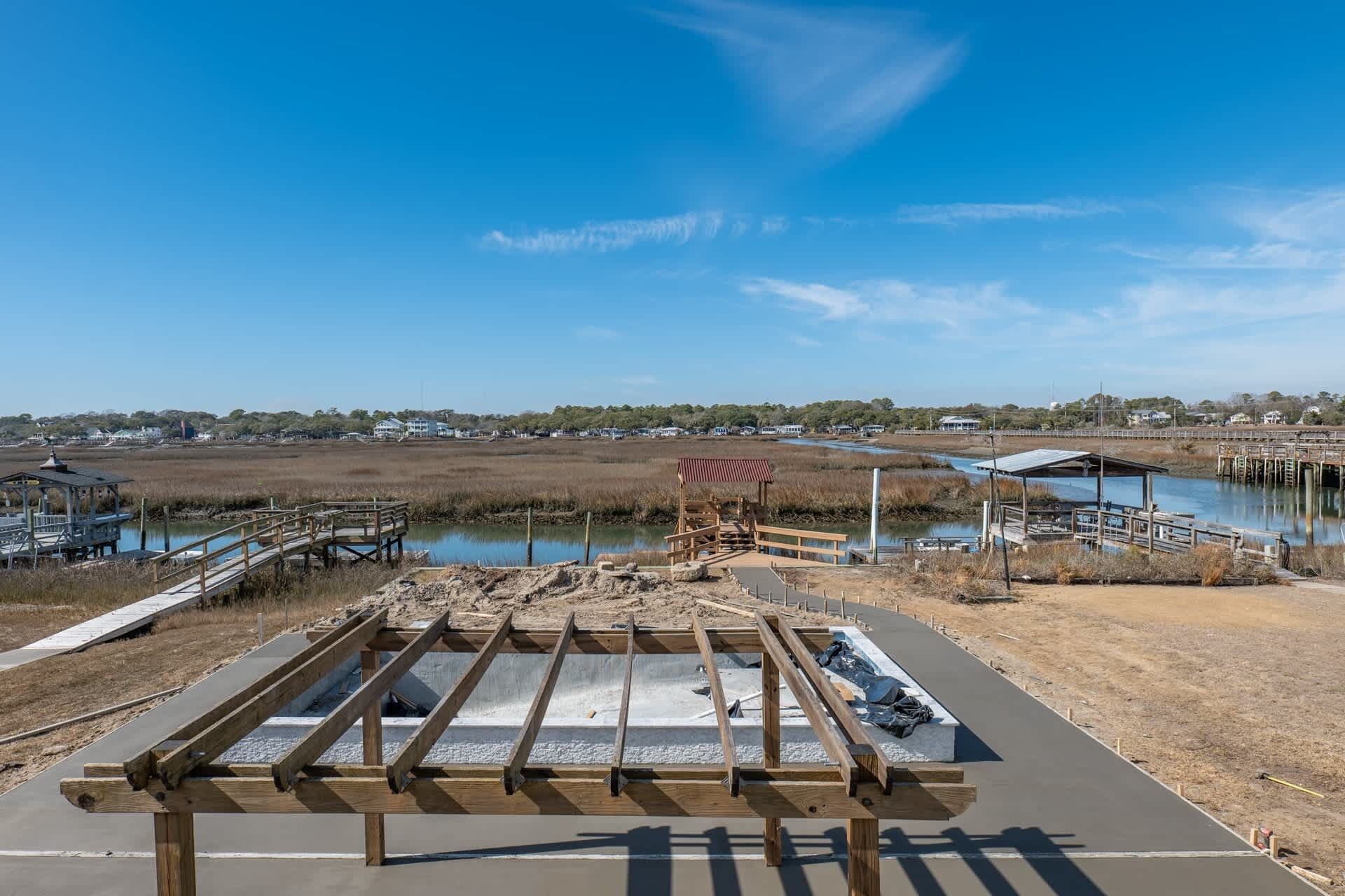 A coastal boardwalk with wooden structures and a clear view of the water.