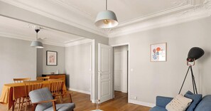 A living room with a dining area, featuring a sofa, chairs, a table, and pendant lighting. - Charme haussmannien - Paris 5e - 1 BDR - 4 pers (Paris)