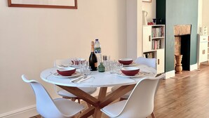 Een eetgedeelte met een ronde tafel, witte stoelen en een fles champagne.