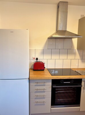 A kitchen with a white refrigerator, a red toaster, a black oven, and a stainless steel range hood. - Spacious Victorian House - E6 London (London)