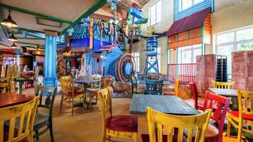 Un restaurante con mesas y sillas de madera, decoración rústica y un ambiente colorido.