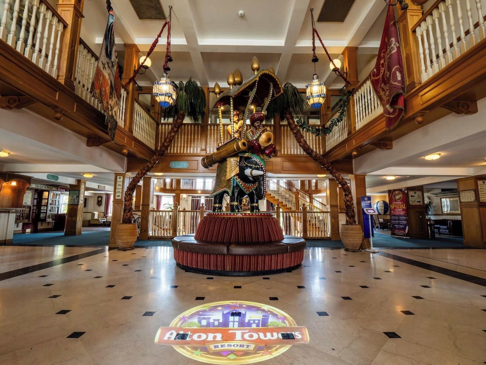A lobby with a central statue, a staircase, and a sign for 'Aiton Town's Resort'.
