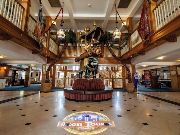 A lobby with a central statue, a staircase, and a sign for 'Aiton Town's Resort'.