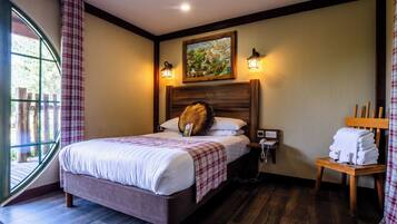 A hotel room with a bed, a nightstand, a lamp, a painting, and a view of the outdoors.