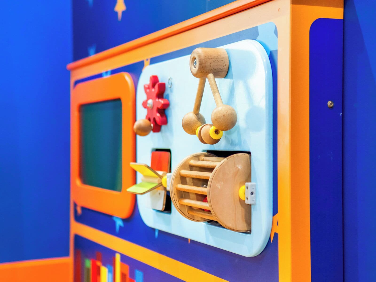 A children's play area with a colorful wall, a small screen, and various toys.