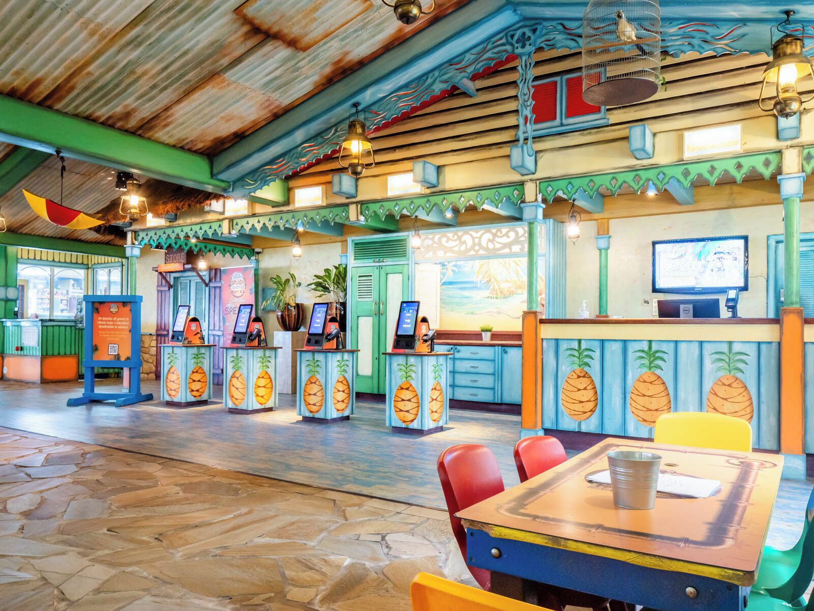 A restaurant with a tropical theme, featuring a counter with a menu, a seating area with tables and chairs, and a ceiling with a corrugated metal design.