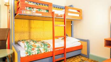 A bunk bed with a ladder, a small table, and a chair in a room with wooden walls and a patterned floor.