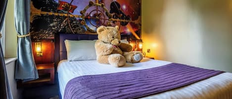 A bed with a purple blanket, a teddy bear, and a wall with a space-themed mural.