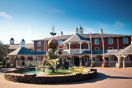A historic building with a central fountain, a covered porch, and a clear blue sky.