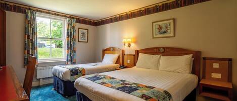 A hotel room with two beds, a desk, and a window with curtains.