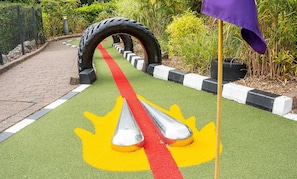 A pathway with a tire arch and a flagpole.