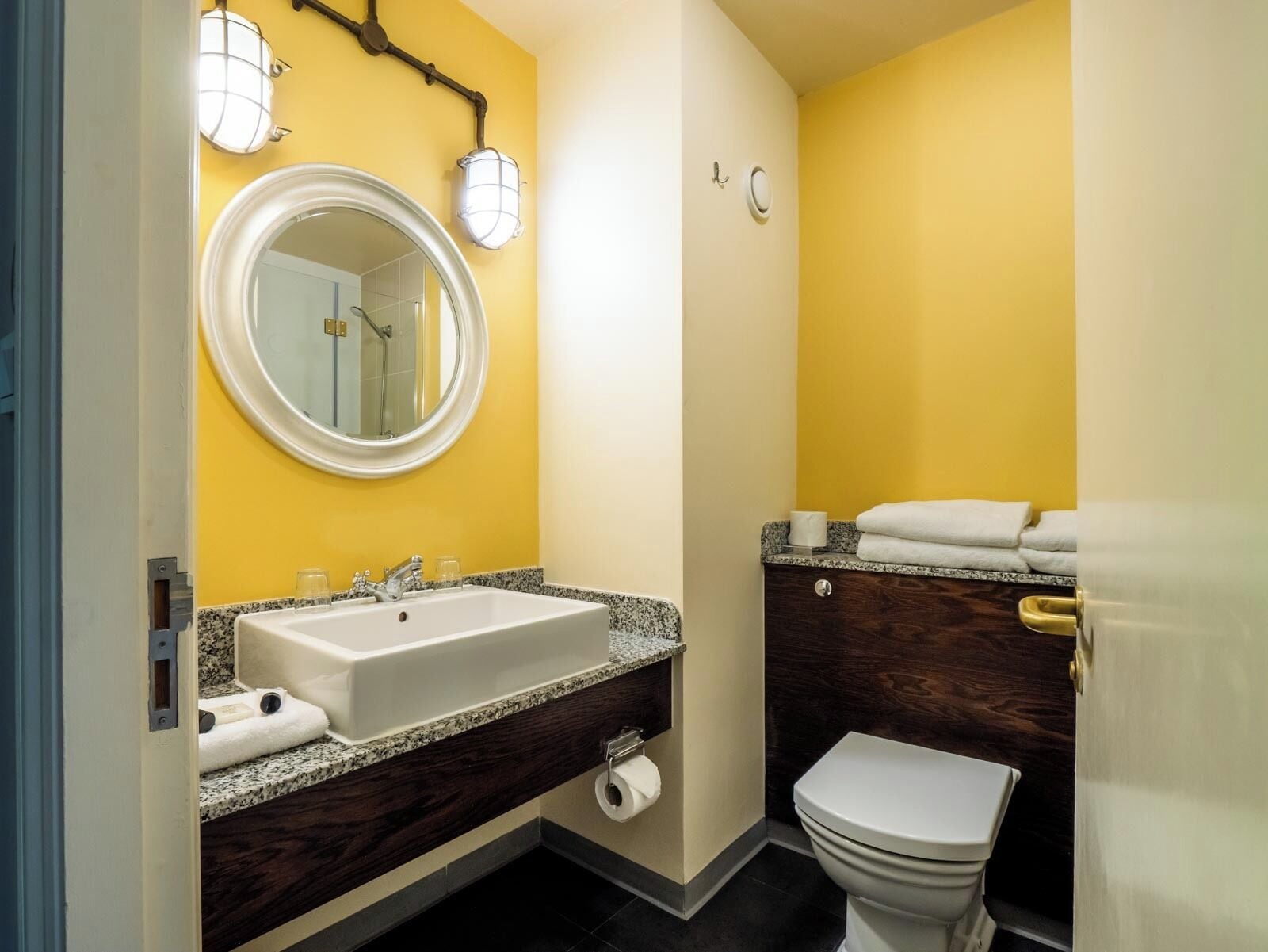 A bathroom with a white sink, a mirror, a toilet, and a towel rack.
