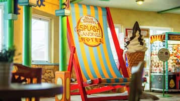 Um sinal colorido com listras para um hotel chamado 'Alton Towers Splash Landings Hotel', com uma grande decoração de sorvete em frente.