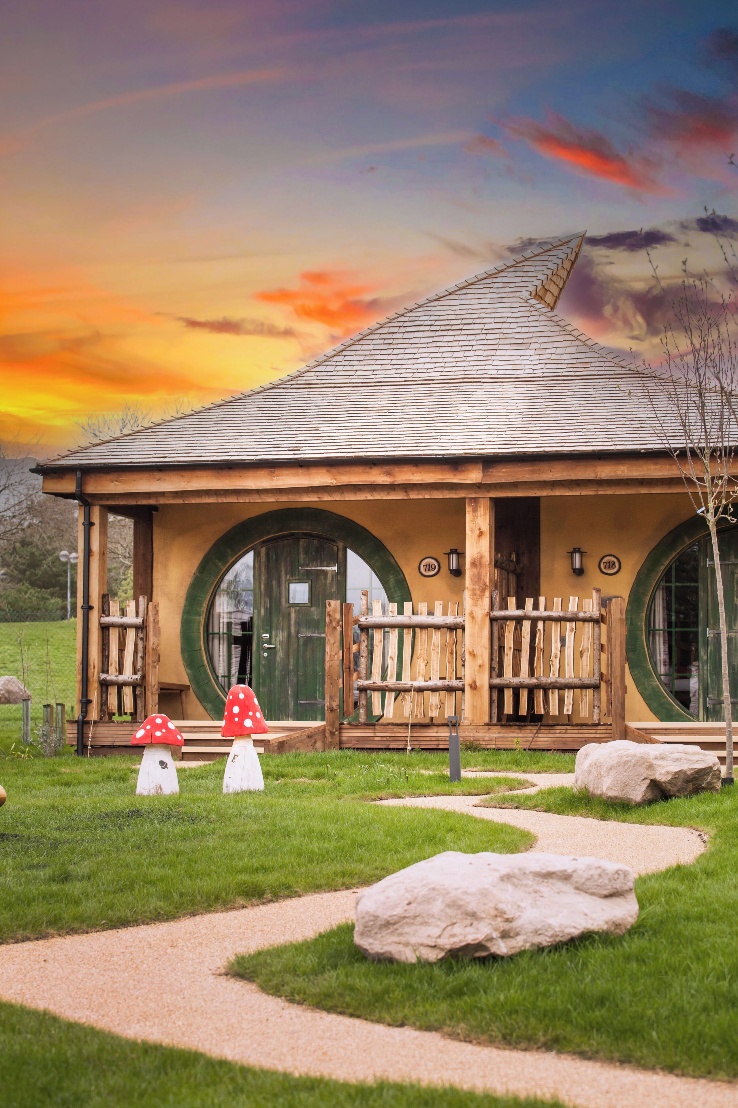 A building with a unique circular window design, a wooden porch, and a mushroom-shaped decoration.