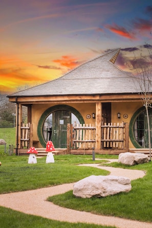 A building with a unique circular window design, a wooden porch, and a mushroom-shaped decoration. - Alton Towers Hotel (Stoke-on-Trent)