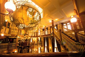 A grand interior with a large globe, wooden staircases, and a welcoming sign.