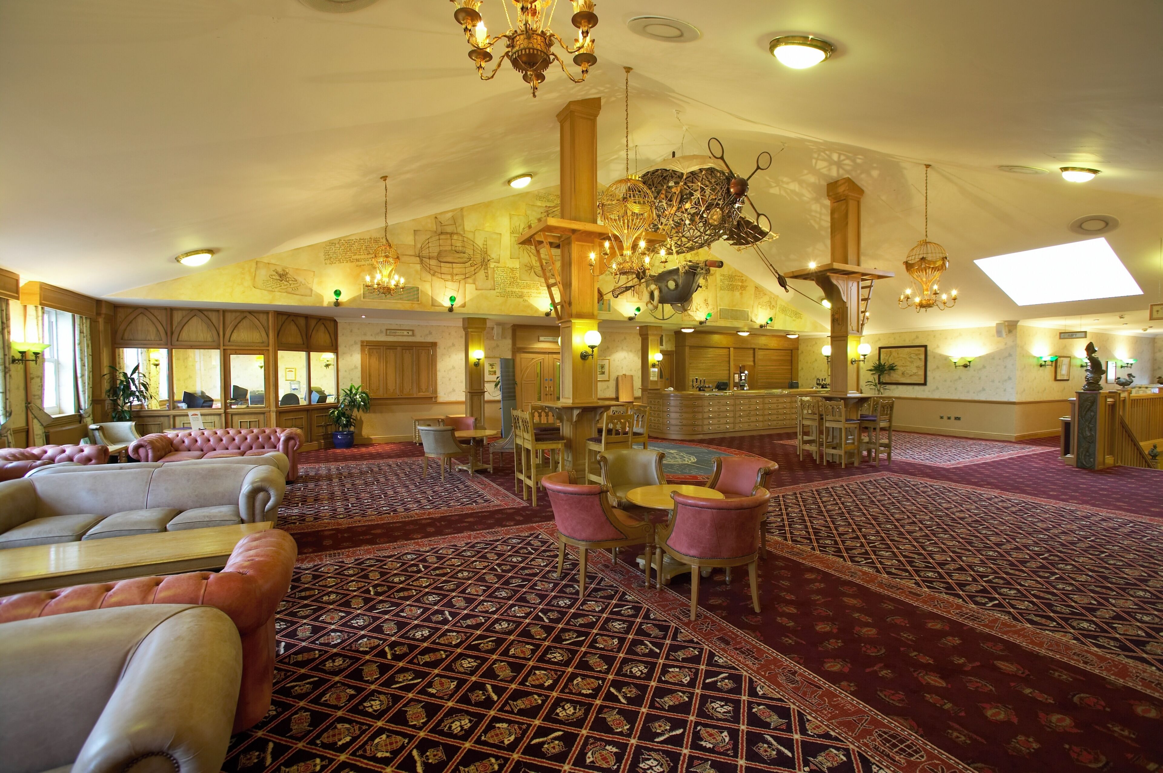 Un espacioso vestíbulo de hotel con techo alto, candelabros ornamentales y una zona de bar central.