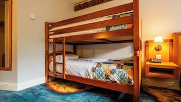 A bunk bed with a quilted bedspread, a bedside lamp, and a bookshelf with books.