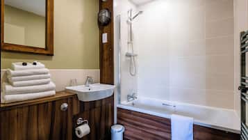 A bathroom with a wooden vanity, a sink, a toilet, a shower, and a bathtub.