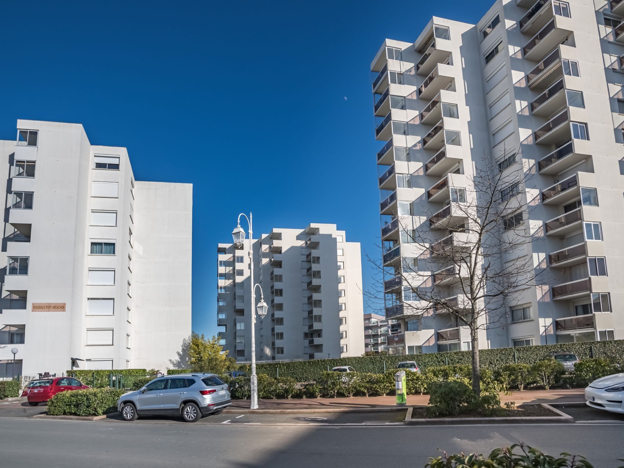 A modern apartment building with multiple balconies and a clear blue sky.