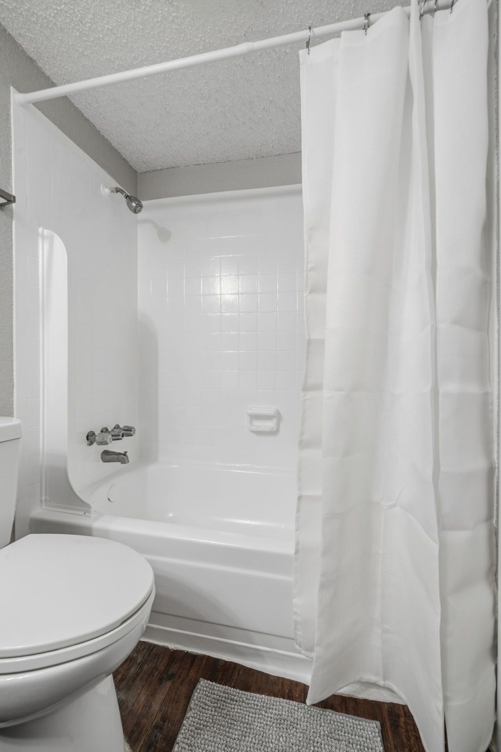 Een badkamer met een wit bad, toilet en douchegordijn.