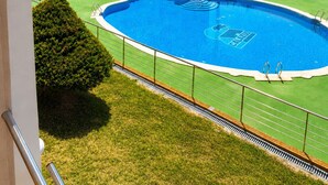 A multi-story building with a swimming pool, palm trees, and a clear sky. - Cala Flores Residence – 3-Bedroom, Pool & Terrace (Cabo de Palos)