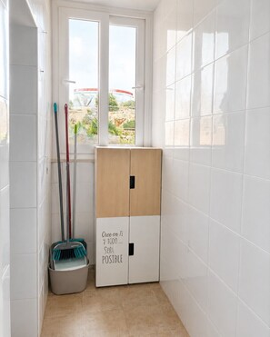 A bathroom with white tiles, a window with a view of greenery, and a cabinet with motivational text. - Cala Flores Residence – 3-Bedroom, Pool & Terrace (Cabo de Palos)