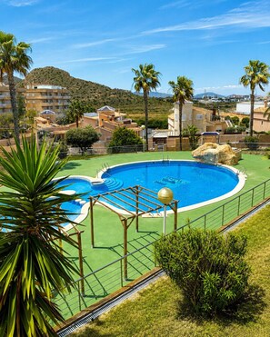 A swimming pool with a surrounding deck, palm trees, and a hilly landscape in the background. - Cala Flores Residence – 3-Bedroom, Pool & Terrace (Cabo de Palos)