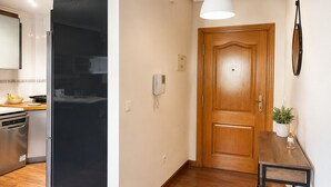 A kitchen with a modern refrigerator, a wooden door, and a small table with a plant. - Cala Flores Residence – 3-Bedroom, Pool & Terrace (Cabo de Palos)
