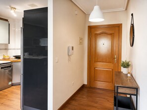 A kitchen with a modern refrigerator, a wooden door, and a small table with a plant. - Cala Flores Residence – 3-Bedroom, Pool & Terrace (Cabo de Palos)