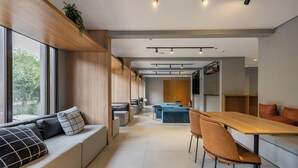A modern interior with a long dining table, seating area with sofas, and a staircase leading to an upper level. - StayHome Chácara Klabin - AC & Gym (São Paulo)