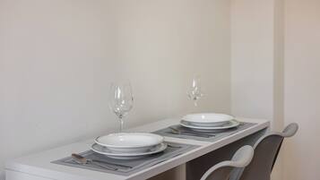 Una mesa de comedor dispuesta con platos, cubiertos y vasos, con una silla al final.