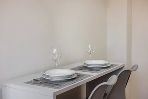 Una mesa de comedor dispuesta con platos, cubiertos y vasos, con una silla al final.