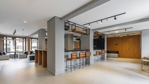 A modern interior with a kitchen area, bar stools, and a seating area with sofas. - StayHome Chácara Klabin - AC & Gym (São Paulo)
