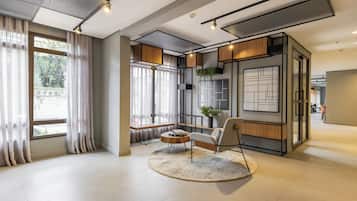 Un interior moderno con un ventanal grande, una mesa de centro redonda, una silla y una planta.