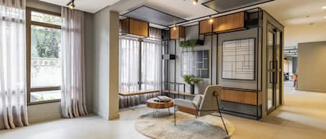 Un interior moderno con un ventanal grande, una mesa de centro redonda, una silla y una planta.