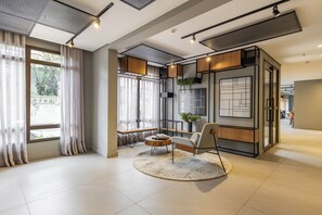 A modern interior with a large window, a round coffee table, a chair, and a plant. - StayHome Chácara Klabin - AC & Gym (São Paulo)