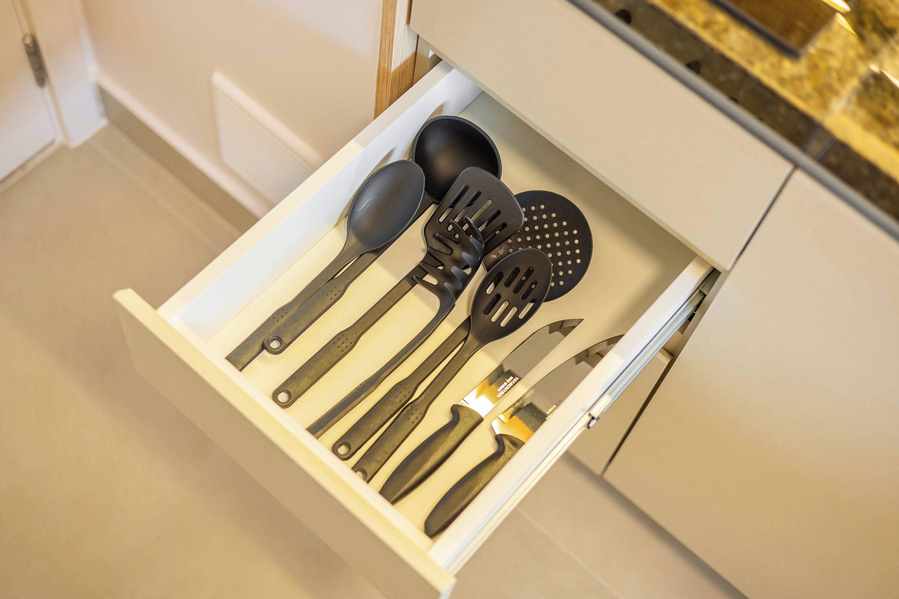 A drawer containing kitchen utensils including a spoon, spatula, and ladle.